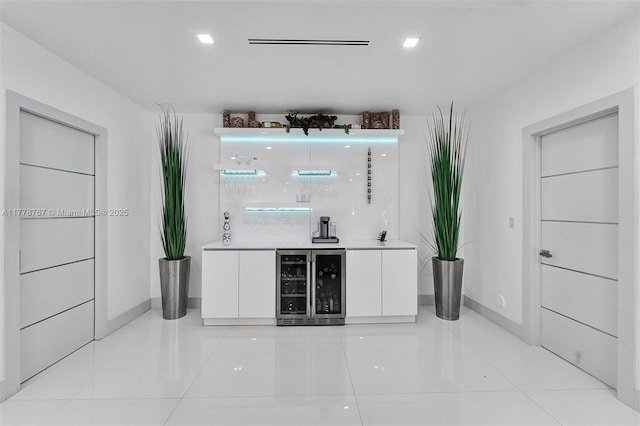 bar with baseboards, beverage cooler, light tile patterned flooring, and a bar