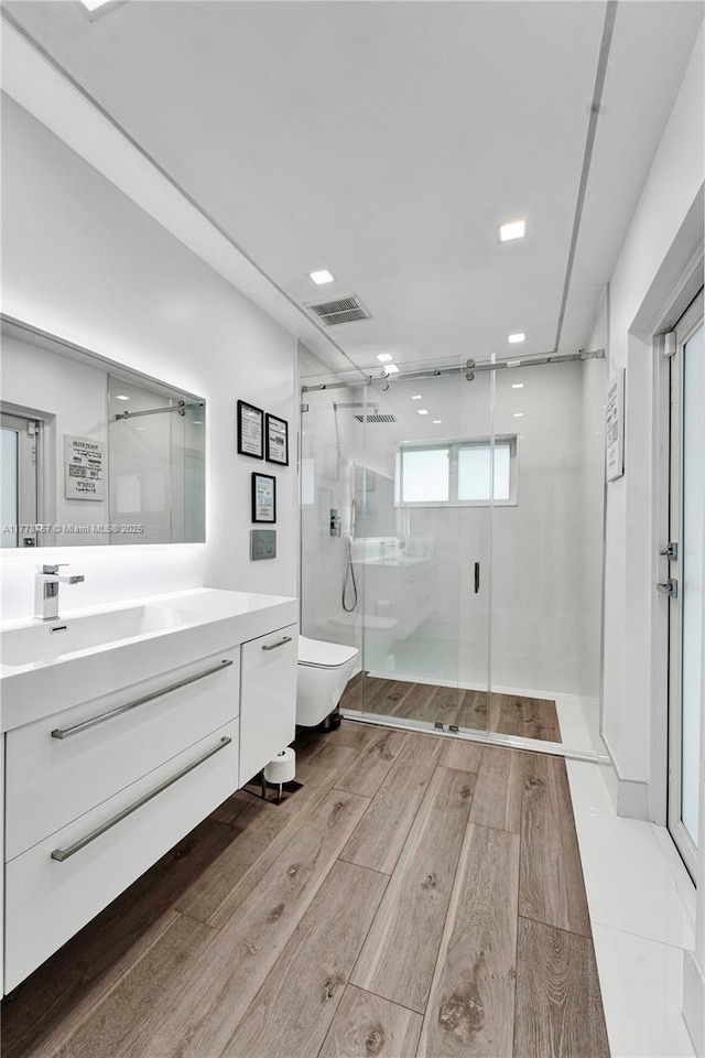 bathroom with visible vents, a shower stall, wood finished floors, vanity, and toilet