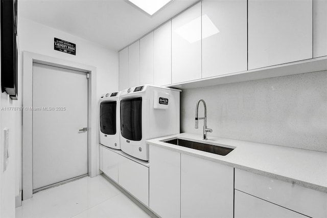 laundry room with cabinet space, light tile patterned floors, a sink, and washer and clothes dryer