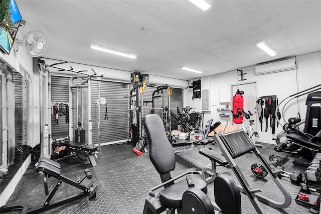 workout area featuring a textured ceiling, electric panel, and a wall mounted air conditioner