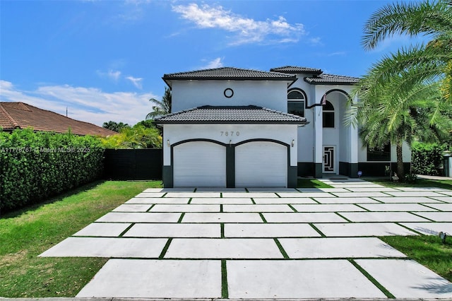 mediterranean / spanish-style home featuring fence, stucco siding, an attached garage, and driveway