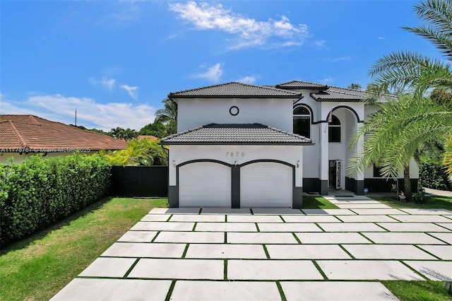 view of front of home with driveway, a tile roof, fence, an attached garage, and stucco siding