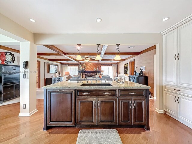 547 Deer Creek Run, Deerfield Beach, FL 33442 - kitchen with dark brown cabinets, a sink, open floor plan, light wood-style floors, and light stone countertops