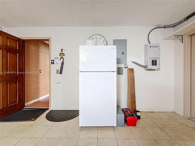 547 Deer Creek Run, Deerfield Beach, FL 33442 - kitchen featuring electric panel, freestanding refrigerator, a textured ceiling, and light tile patterned floors