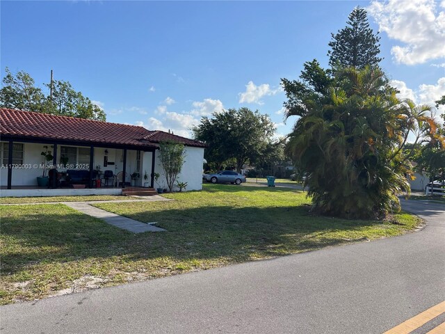 1001 NE 111th St, Biscayne Park, FL 33161 - view of front of property featuring stucco siding, a front lawn, a porch, and a tile roof