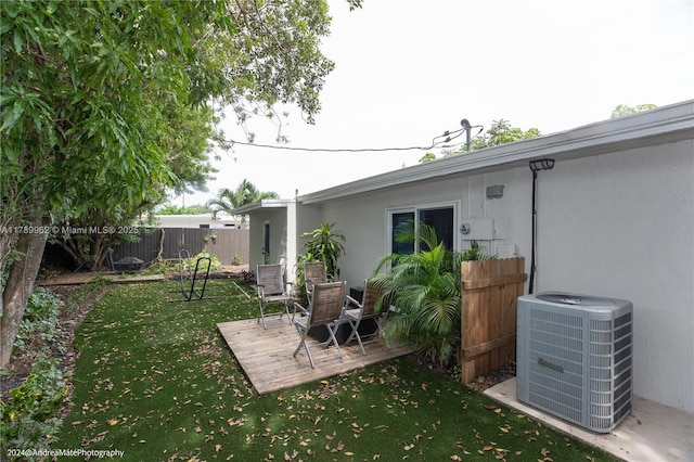 5901 NE 4th Ave, Oakland Park, FL 33334 - rear view of house featuring central AC unit, a lawn, fence, stucco siding, and a wooden deck