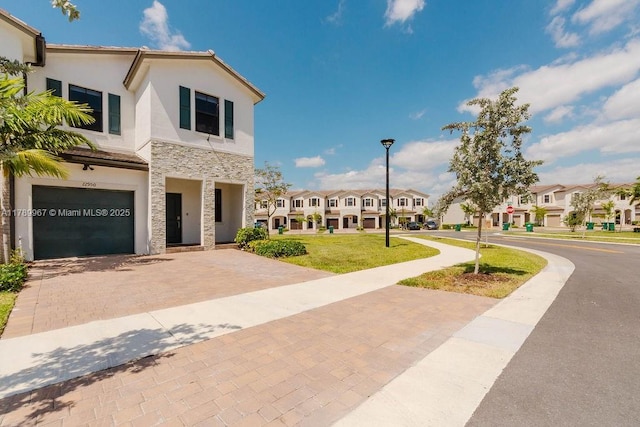 12950 SW 235th Ter, Homestead, FL 33032 - view of front of house featuring decorative driveway, stone siding, an attached garage, stucco siding, and a residential view