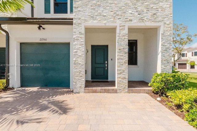 12950 SW 235th Ter, Homestead, FL 33032 - entrance to property featuring an attached garage, stone siding, and stucco siding