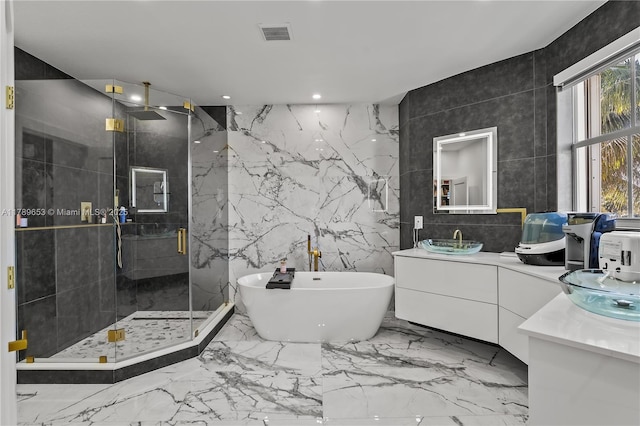 bathroom with tile walls, a marble finish shower, vanity, and toilet