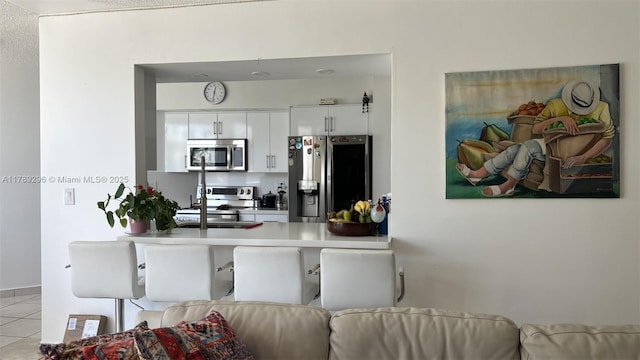 16485 E Collins Ave Unit 338, Sunny Isles Beach, FL 33160 - kitchen featuring a peninsula, light countertops, white cabinetry, appliances with stainless steel finishes, and light tile patterned floors