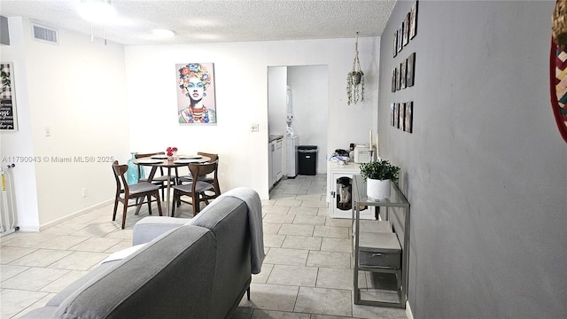 living room with a textured ceiling, visible vents, and light tile patterned floors