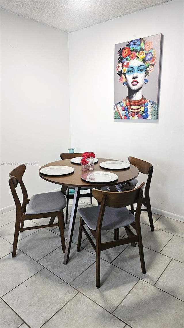 dining room with baseboards, light tile patterned flooring, and a textured ceiling