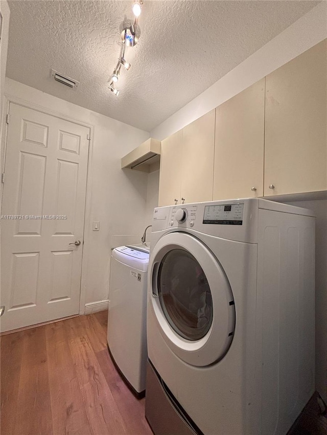 320 Windmill Palm Ave, Plantation, FL 33324 - laundry area featuring cabinet space, light wood-style flooring, washer and dryer, and a textured ceiling