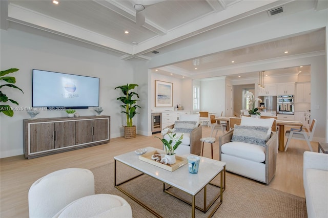living area with beverage cooler, light wood-style flooring, crown molding, and beamed ceiling