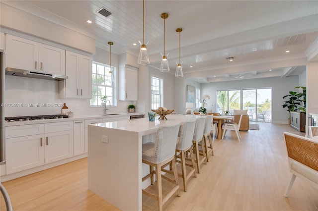 kitchen featuring black gas cooktop, open floor plan, light wood-type flooring, under cabinet range hood, and visible vents