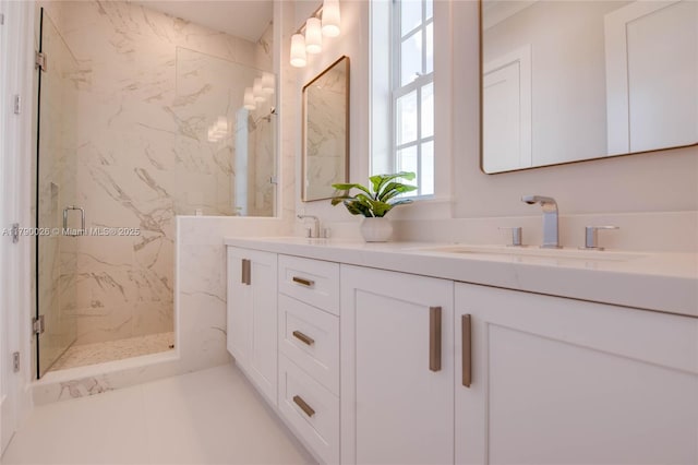 bathroom with double vanity, a marble finish shower, and a sink