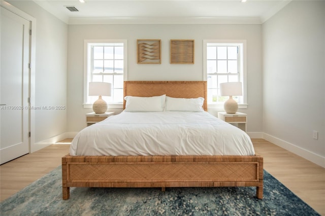 bedroom with visible vents, crown molding, wood finished floors, and multiple windows