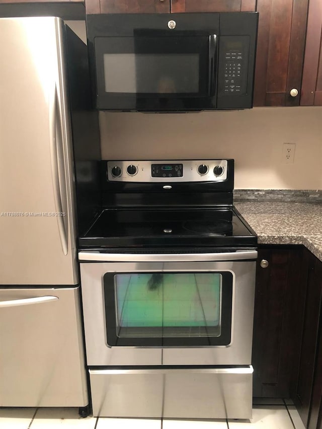 kitchen with stainless steel electric stove, dark countertops, freestanding refrigerator, dark brown cabinetry, and black microwave