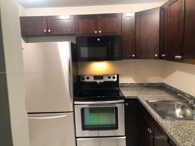kitchen featuring dark countertops, dark brown cabinetry, stainless steel appliances, and a sink