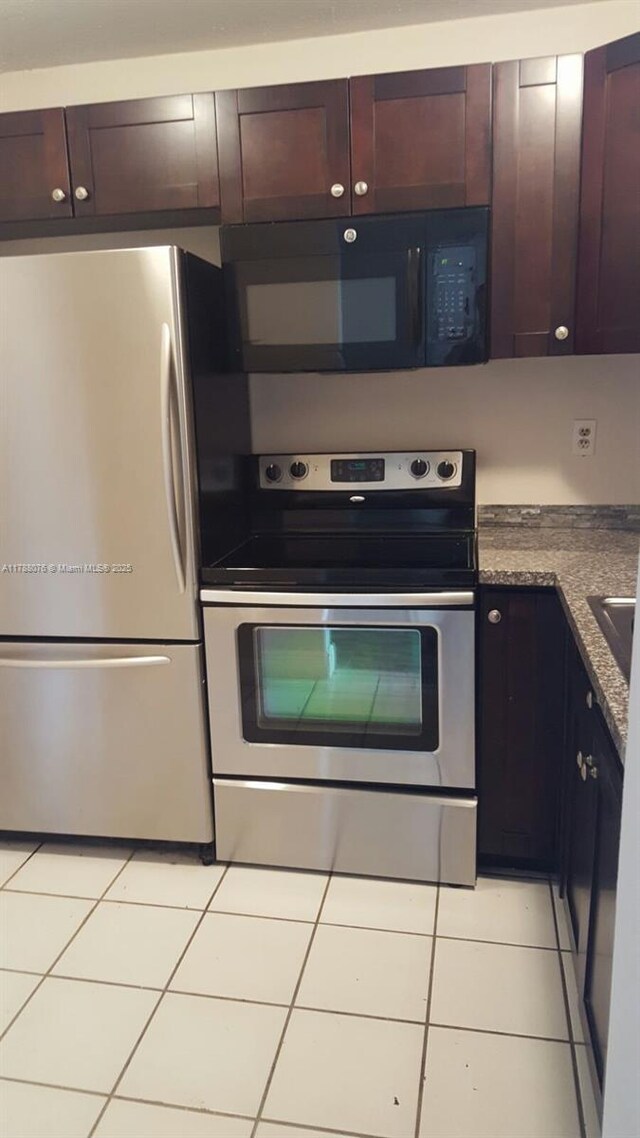 kitchen featuring dark brown cabinetry, light tile patterned flooring, and stainless steel appliances