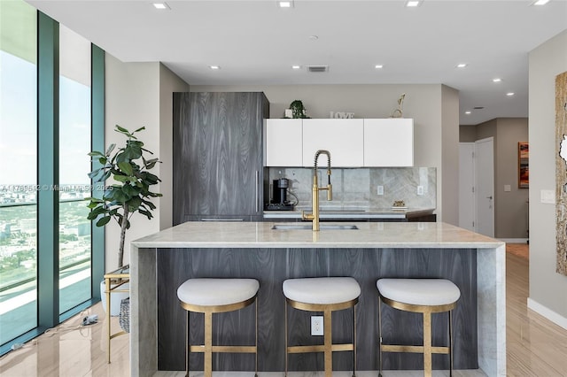 480 NE 31st St Unit 4701, Miami, FL 33137 - kitchen featuring white cabinets, a breakfast bar, modern cabinets, a sink, and tasteful backsplash