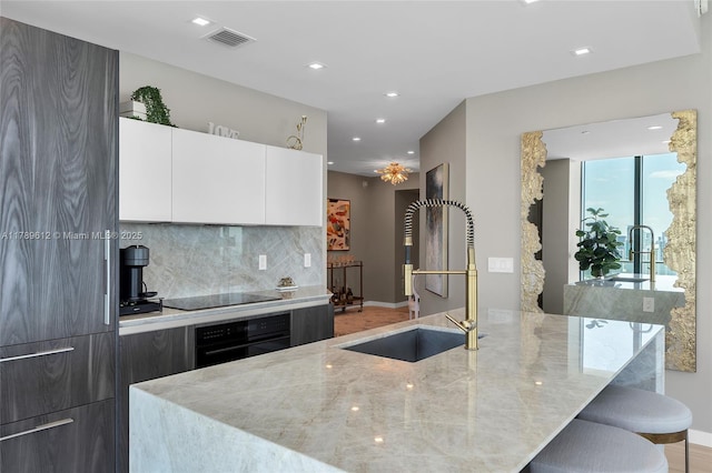 480 NE 31st St Unit 4701, Miami, FL 33137 - kitchen with tasteful backsplash, modern cabinets, light stone counters, and black appliances