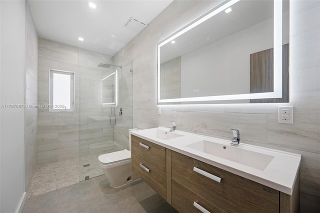 full bath featuring tile walls, toilet, a stall shower, and a sink