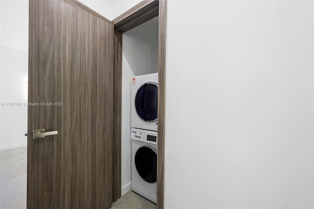 laundry area with stacked washing maching and dryer, light tile patterned floors, and laundry area