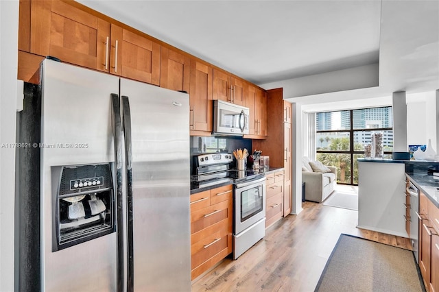 600 Parkview Dr Unit 422, Hallandale Beach, FL 33009 - kitchen with stainless steel appliances, brown cabinets, dark countertops, light wood finished floors, and open floor plan
