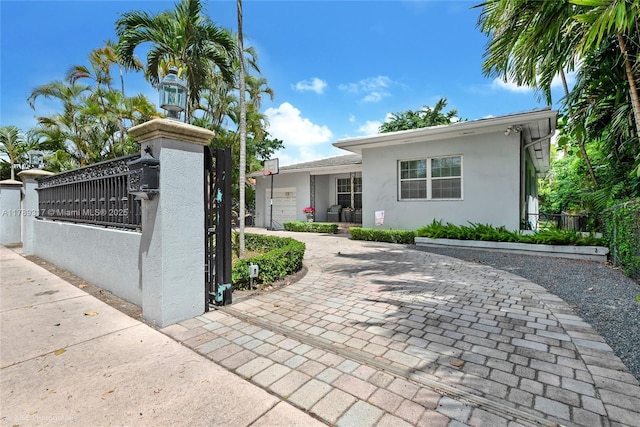 ranch-style home featuring a gate, stucco siding, and a fenced front yard