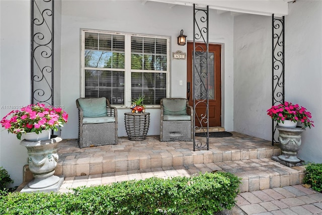 view of exterior entry featuring a porch and stucco siding