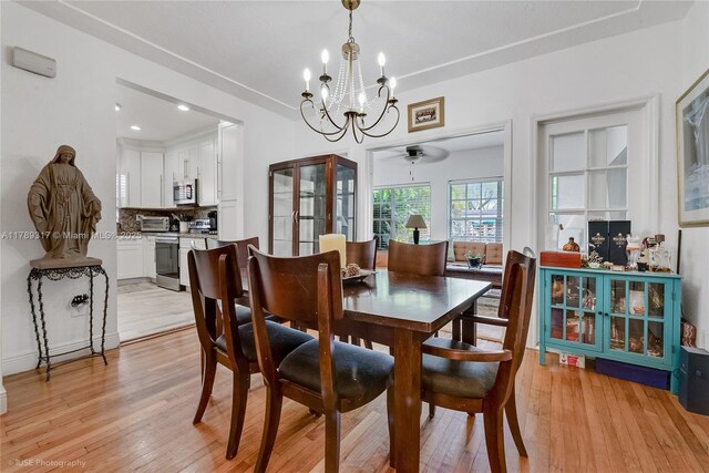dining area featuring a toaster, light wood finished floors, and ceiling fan with notable chandelier