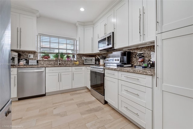 kitchen with a sink, white cabinets, appliances with stainless steel finishes, and tasteful backsplash