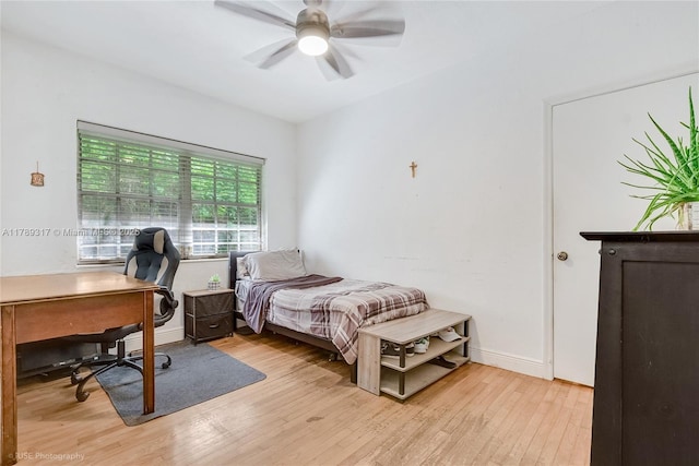 bedroom with ceiling fan, light wood-style flooring, and baseboards