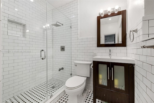 bathroom with tile walls, a stall shower, toilet, and vanity
