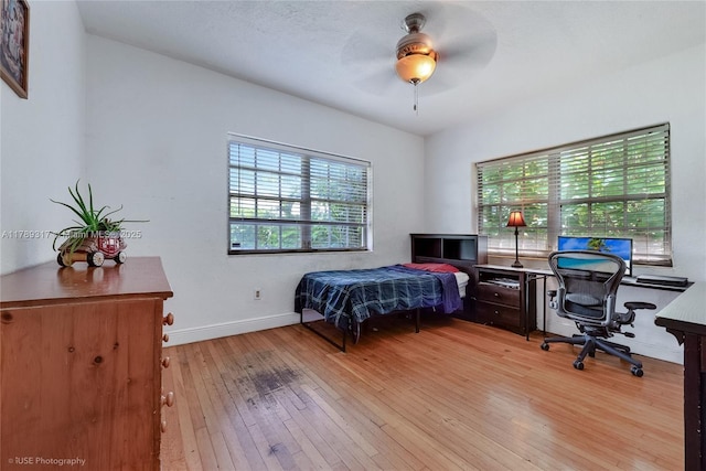 bedroom featuring ceiling fan, light wood-style flooring, and baseboards