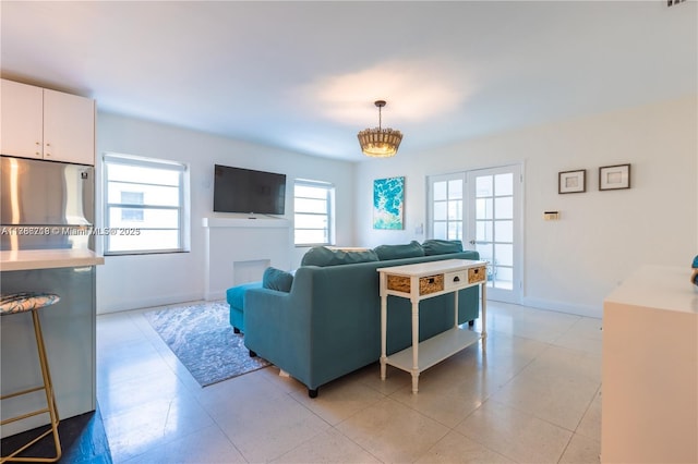 living area featuring light tile patterned floors, an inviting chandelier, and baseboards
