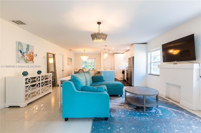 living area with a chandelier, visible vents, a healthy amount of sunlight, and baseboards