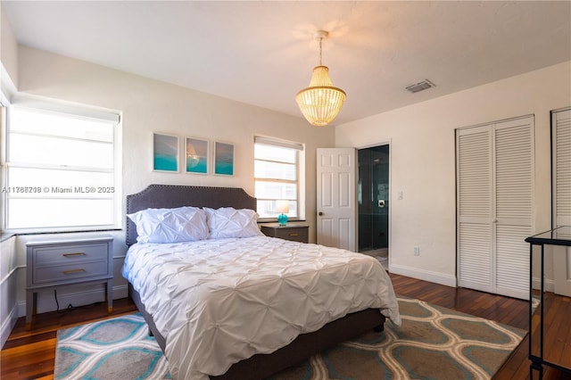 bedroom with visible vents, baseboards, a notable chandelier, and wood-type flooring