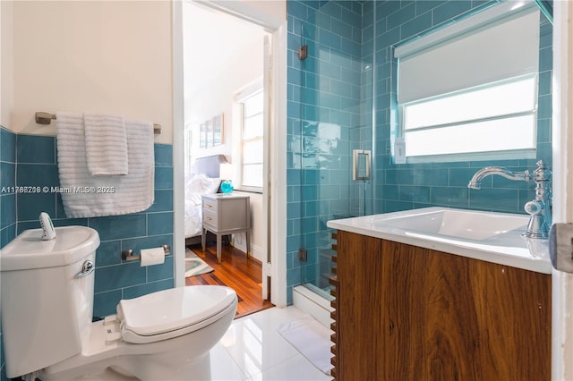 full bath featuring toilet, a stall shower, tile walls, and vanity