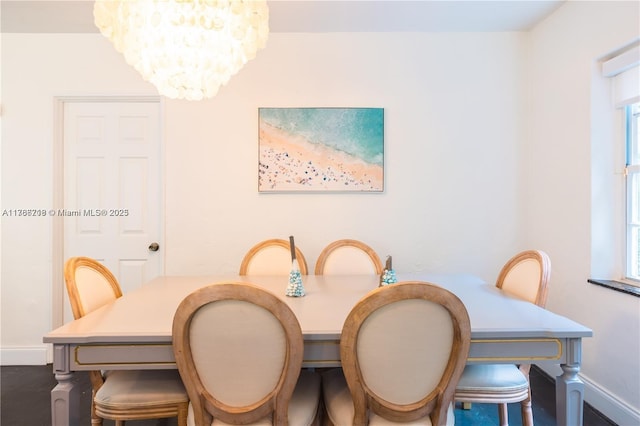 dining area featuring a chandelier and baseboards