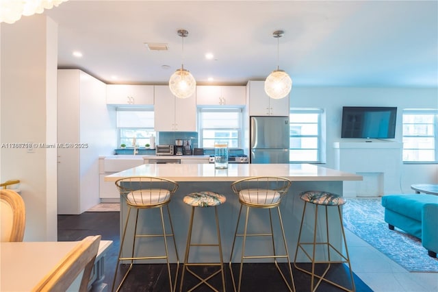 kitchen featuring a kitchen breakfast bar, white cabinetry, stainless steel appliances, and visible vents