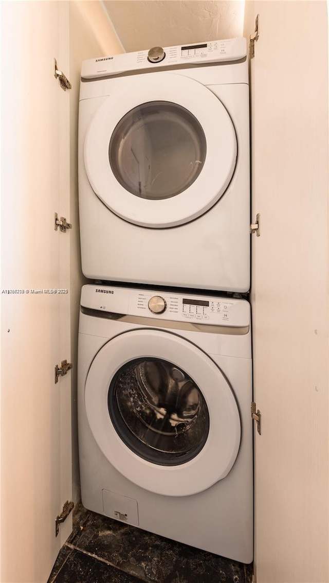 laundry area with stacked washer and dryer, marble finish floor, and laundry area
