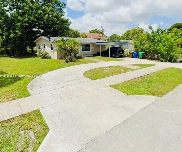 single story home featuring a carport, concrete driveway, and a front yard