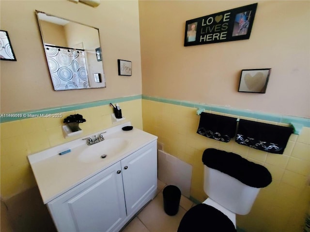 full bathroom with tile walls, a wainscoted wall, toilet, and vanity