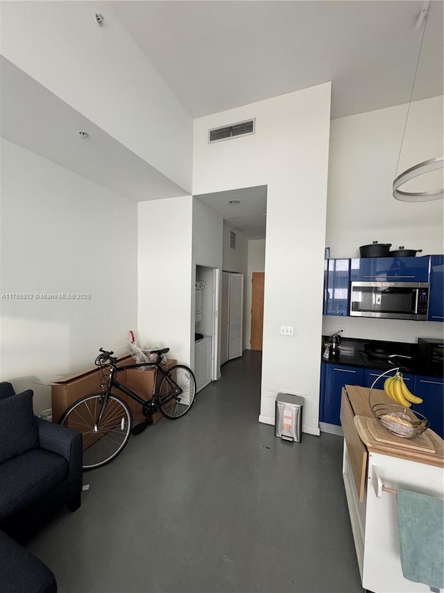 253 NE 2nd St Unit 324, Miami, FL 33132 - kitchen with stainless steel microwave, blue cabinets, finished concrete floors, dark countertops, and open floor plan