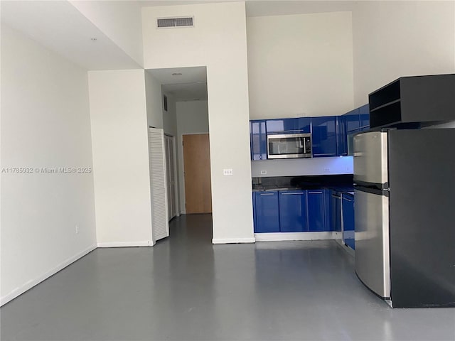 253 NE 2nd St Unit 324, Miami, FL 33132 - kitchen with appliances with stainless steel finishes, blue cabinets, dark countertops, finished concrete floors, and baseboards