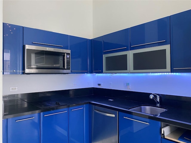 253 NE 2nd St Unit 324, Miami, FL 33132 - kitchen with stainless steel microwave, a sink, black electric stovetop, blue cabinets, and dark countertops