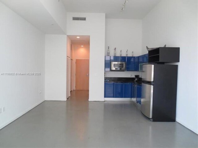 253 NE 2nd St Unit 324, Miami, FL 33132 - kitchen with appliances with stainless steel finishes, blue cabinets, dark countertops, and finished concrete floors