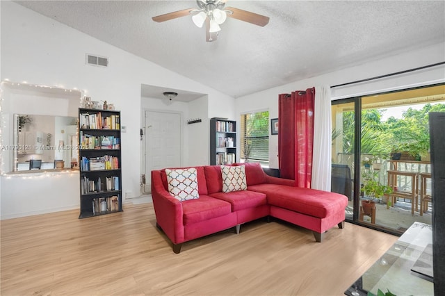 living room featuring a textured ceiling, visible vents, vaulted ceiling, wood finished floors, and a ceiling fan